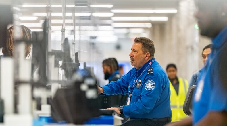 A Transportation Security Administration officer checks the identification of travelers at Hartsfield-Jackson Atlanta International Airport on Wednesday, Oct. 1, 2025. (Ben Hendren for the AJC)