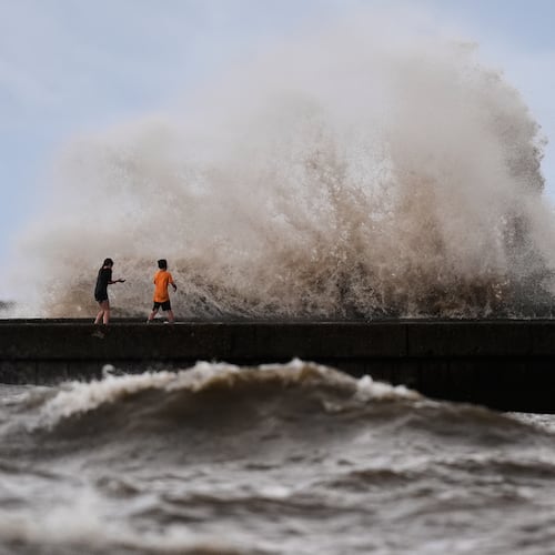 Children play near breaking waves on West End Pier on Lake Pontchartrain as Tropical Storm Bertha approaches the Louisiana Coast Wednesday, July 22, 2026, in New Orleans. (AP Photo/Gerald Herbert)