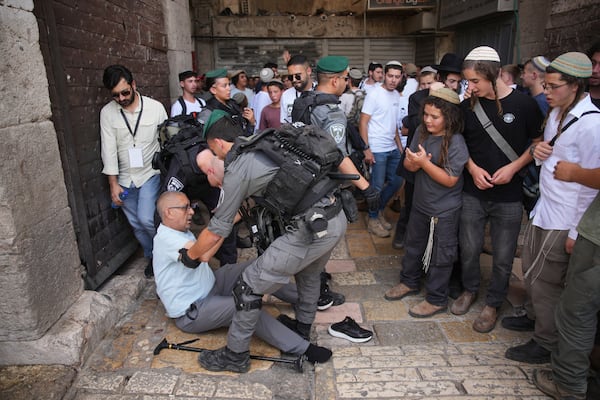Israeli police officers assist a Palestinian man after he was pushed by right wing Israelis as they mark Jerusalem Day, an Israeli holiday celebrating the capture of east Jerusalem in the 1967 Mideast war, in Jerusalem's Old City, Monday, May 26, 2025. (AP Photo/Ohad Zwigenberg)