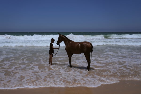 Palestinian youth Mahmoud Abu Ghazal washes his horse in the Mediterranean Sea off the coast of Al-Zawida in central Gaza Strip, Tuesday, July 15, 2025. (AP Photo/Abdel Kareem Hana)