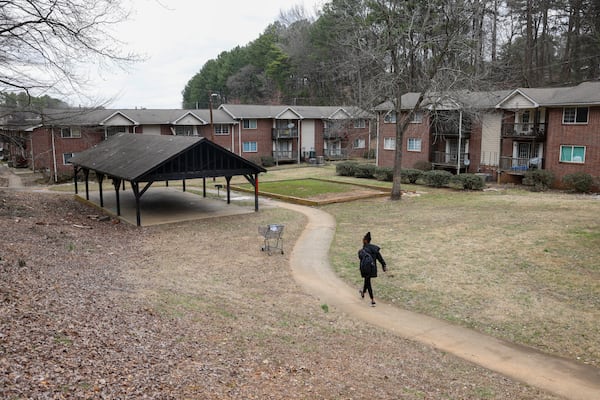 A woman walks in February toward an empty patch of grass where a playground used to stand at Pavilion Place apartments. The worn-out equipment was dismantled after a crackdown on conditions at the complex. (Jason Getz/Jason.Getz@ajc.com)
