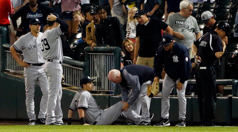 New York Yankees' Dustin Fowler is checked by a team trainer after an injury during the first inning of the team's baseball game against the Chicago White Sox on Thursday, June 29, 2017, in Chicago.