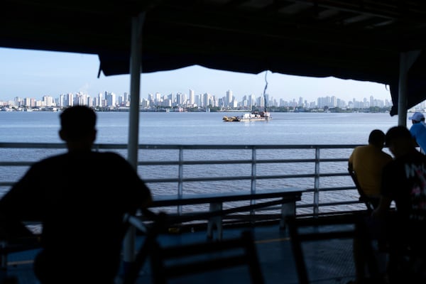 FILE - People look out at the coast of Belem, Brazil, as a boat nears shore, March 23, 2025. (AP Photo/Jorge Saenz, File)