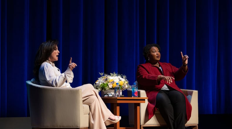 Stacey Abrams, right, raises a hand to quiet the crowd while talking in San Antonio about voting rights.