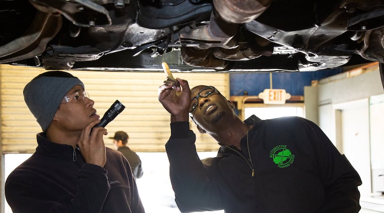 Student, Brandon Oates (left) and instructor Larry Witherspoon Jr. inspect a vehicle on a lift at the Automotive Training Center in East Point. Photo by Phil Skinner