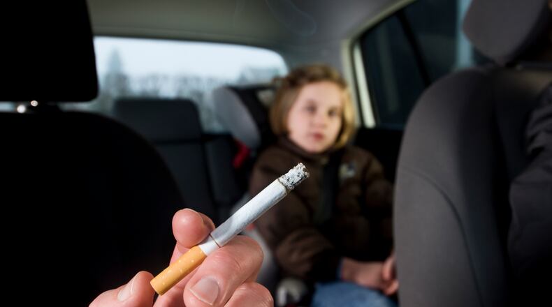 Woman smoking with child in car (stock photo)