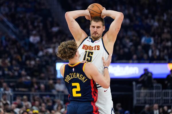 Denver Nuggets center Nikola Jokic (15) looks for an open teammate while defended by Golden State Warriors guard Brandin Podziemski (2) during the first half of an NBA basketball game Friday, April 4, 2025, in San Francisco. (AP Photo/Godofredo A. Vásquez)