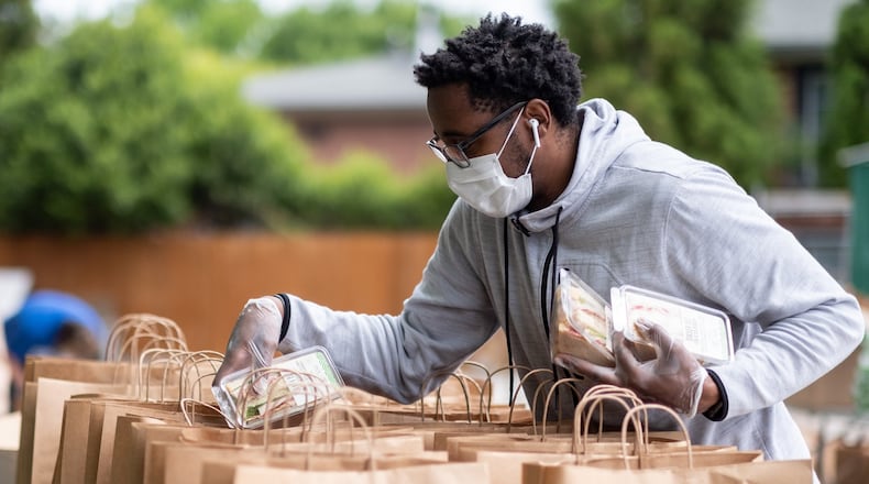 Erik Roberson with CHRIS 180 stuffs bags with food to be distributed to those in need on Friday, April 24, 2020. Ben@BenGray.com for the Atlanta Journal-Constitution