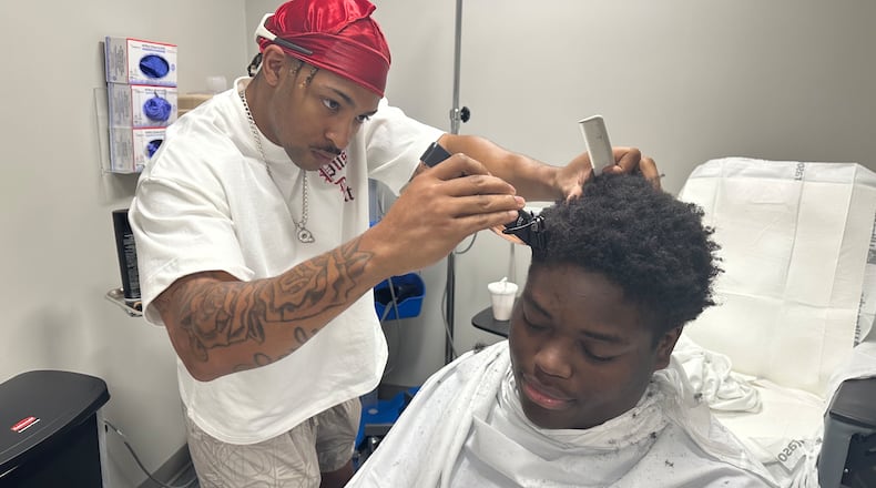 Nurses at Piedmont Newton Hospital infusion center in Covington rallied their community to help Malik King attend his senior prom. King is being treated for lymphoma at the center and going to his prom was a big deal to him. Firefighter Q Glenn (left) of Rockdale Fire Station 1, also a barber, trimmed Malik's hair during one of his treatments. Courtesy of Piedmont Newton Hospital