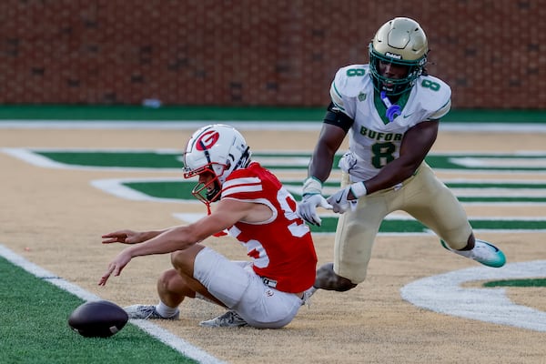 Gainesville punter Logan Gailey (left) fumbles the snap near the end zone as Buford's Joshua Echols applies pressure Saturday, Aug. 22, 2026, in Buford. (Erik S. Lesser for the AJC)