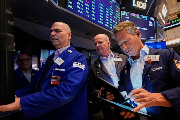 Specialist Philip Finale, left, works with traders Patrick Casey, center, and Robert Charmak on the floor of the New York Stock Exchange, Tuesday, April 22, 2025. (AP Photo/Richard Drew)