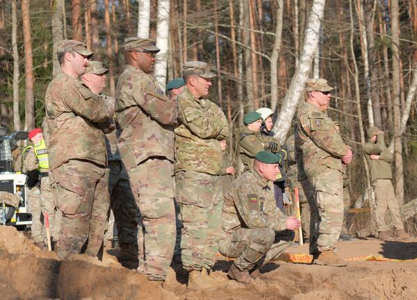 In this image provided by the U.S. Army, U.S. Army soldiers from the 1st Armored Brigade Combat Team, 3rd Infantry Division, along with Lithuanian Army and emergency services personnel, watch as an excavator builds a dam during recovery efforts for four U.S. soldiers in a U.S. Army M88 Hercules submerged under several meters of water and in a swamp near a training area near Pabadre, Lithuania, Thursday, March 27, 2025. (Christopher Saundersn/U.S. Army via AP)