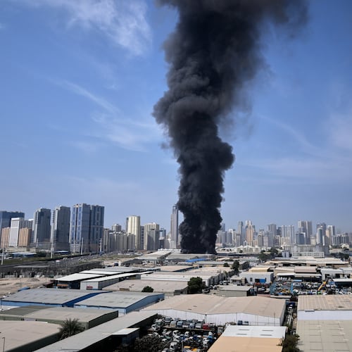 A black plume of smoke rises from a warehouse at the industrial area of Sharjah City in the United Arab Emirates following reports of Iranian strikes in Dubai, United Arab Emirates, Sunday, March 1, 2026. (AP Photo/Altaf Qadri)