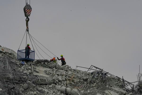Rescuers make their way in from the top of debris to look for survivors from an under-construction high-rise building that collapsed after an earthquake in Bangkok, Thailand, Monday, March, 31, 2025. (AP Photo/Manish Swarup)