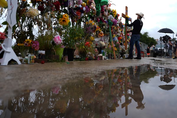 Roberto Marquez places a cross at a memorial wall for flood victims, Sunday, July 13, 2025, in Kerrville, Texas. (AP Photo/Eric Gay)