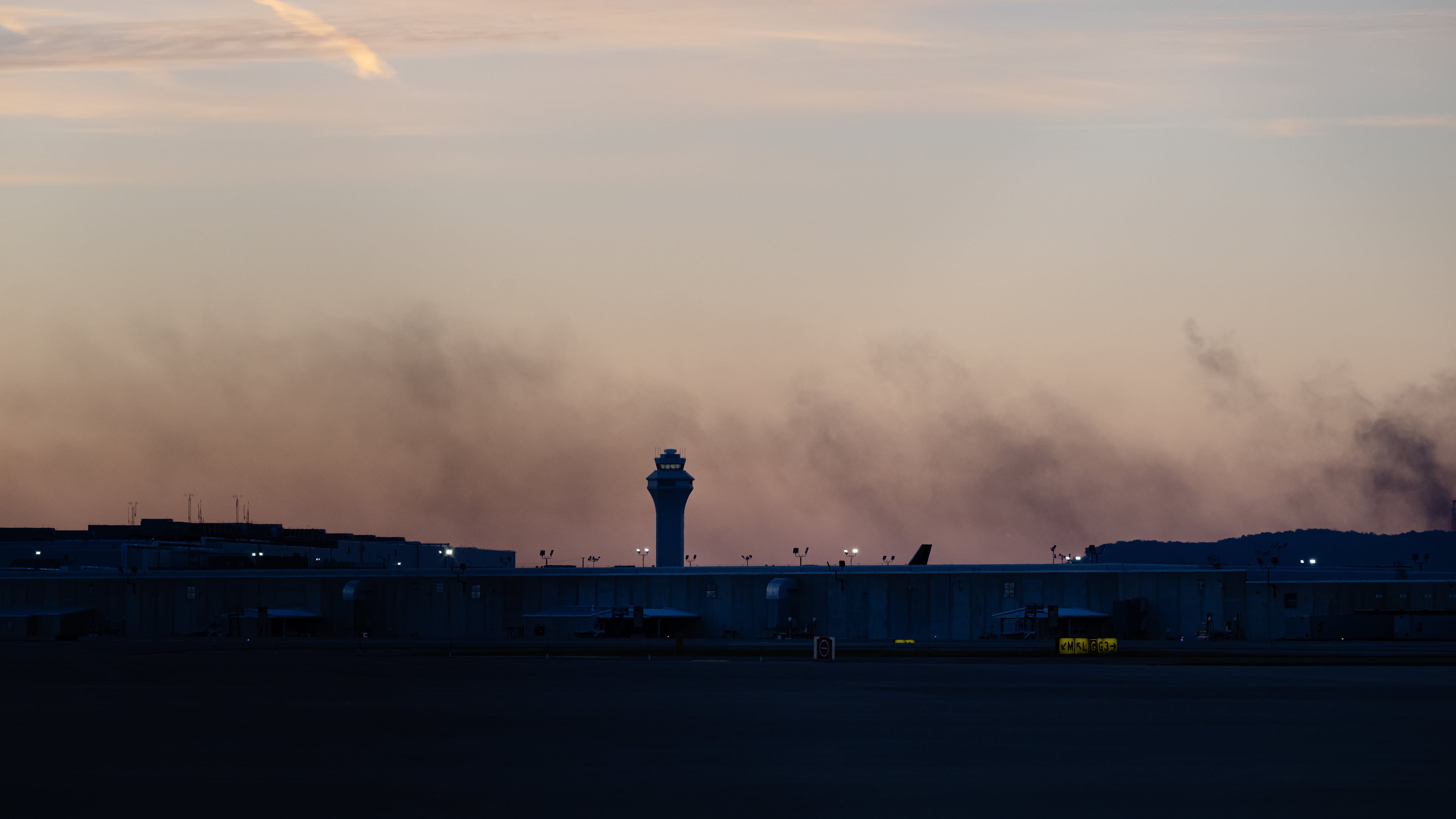 CORRECTS FLIGHT NUMBER The ATC tower is seen while smoke rises from the crash site of UPS Flight 2976 near Louisville Muhammad Ali International Airport on Wednesday, Nov. 5, 2025, in Louisville, Ky. (AP Photo/Jon Cherry)