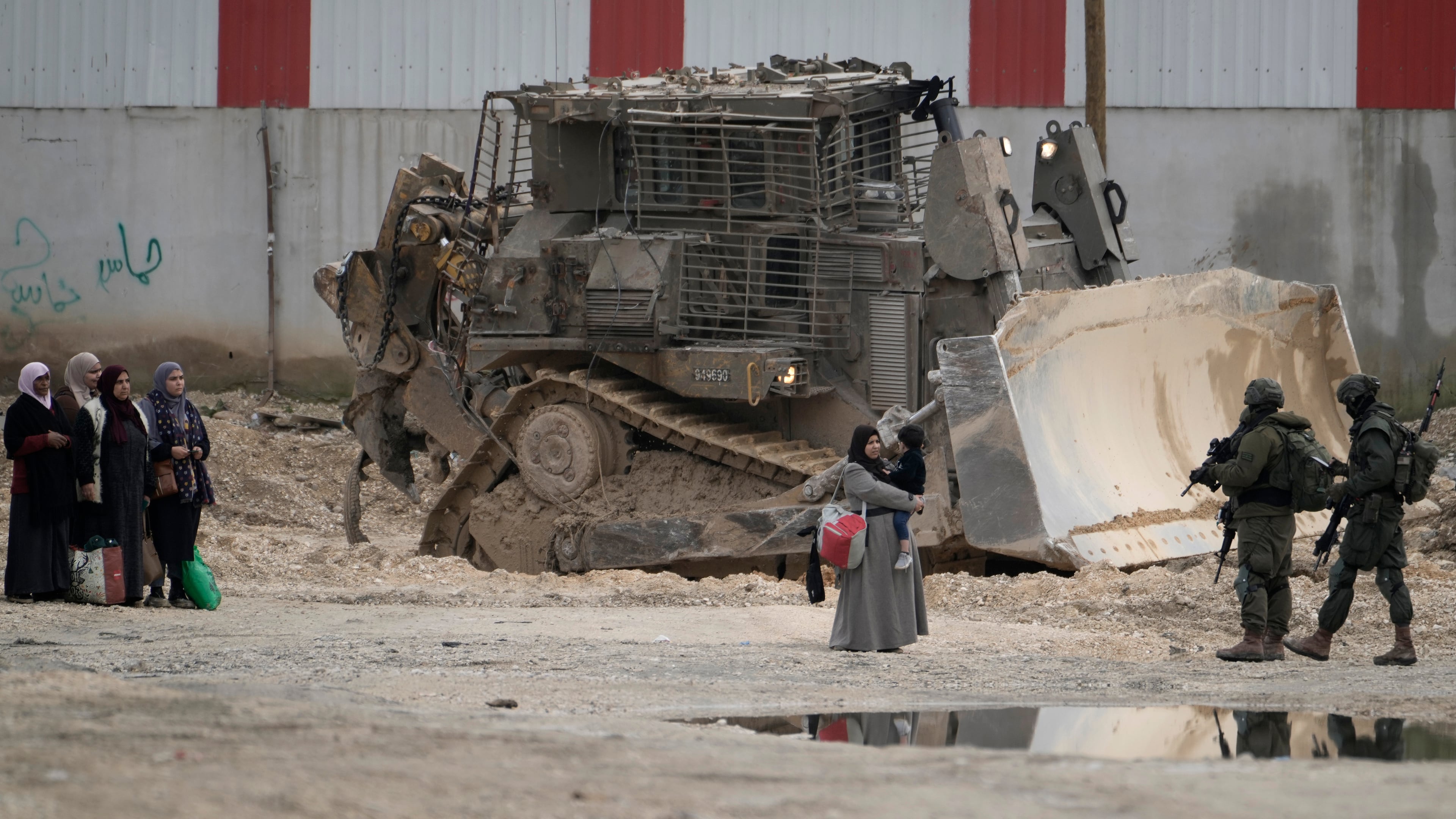 FILE -Israeli soldiers check the identification cards of Palestinians while they evacuate their homes in the West Bank refugee camp of Nur Shams, near Tulkarem, while the Israeli military operation continues in the area on, Feb. 11, 2025. (AP Photo/Majdi Mohammed, File)