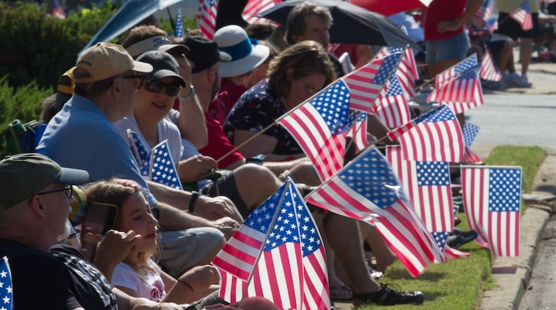 Spectators wave their flags as the Marietta Freedom Parade makes its way down Roswell Street on Tuesday, July 4, 2016, In Marietta, GA. An estimated 30,000 spectators turned out for the parade. STEVE SCHAEFER / SPECIAL TO THE AJC