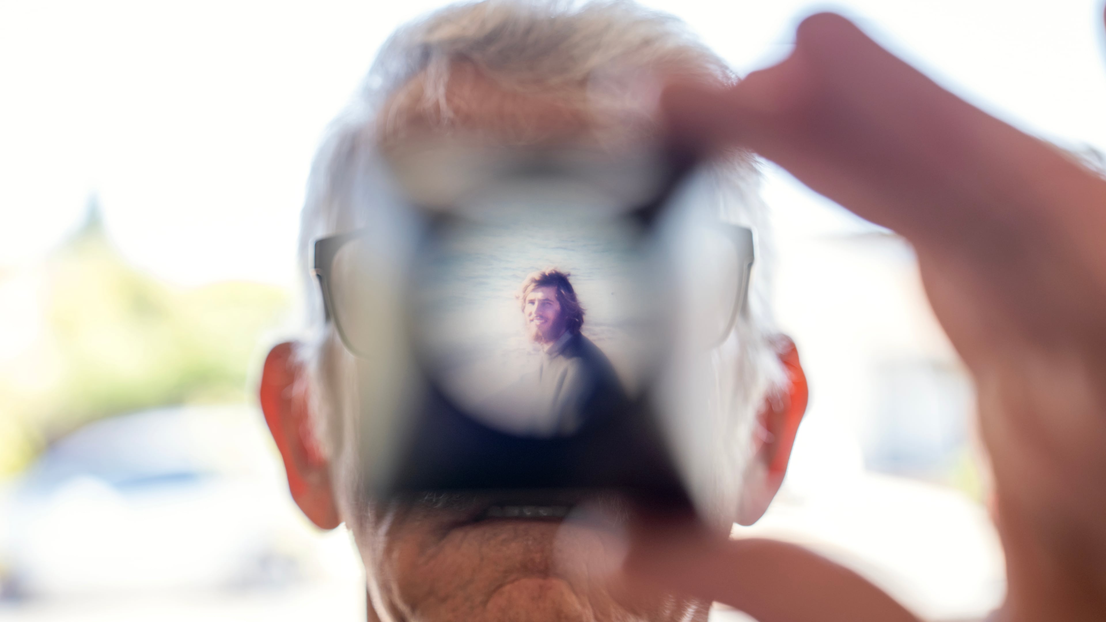 Christy Morrill, 72, who lost decades of memories to autoimmune encephalitis, holds up a viewfinder with a slide film of himself as a college student, Wednesday, Aug. 20, 2025, at his home in San Carlos, Calif. (AP Photo/David Goldman)