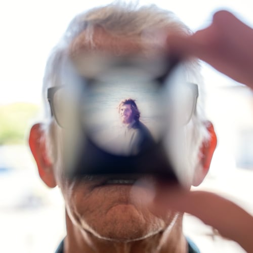 Christy Morrill, 72, who lost decades of memories to autoimmune encephalitis, holds up a viewfinder with a slide film of himself as a college student, Wednesday, Aug. 20, 2025, at his home in San Carlos, Calif. (AP Photo/David Goldman)