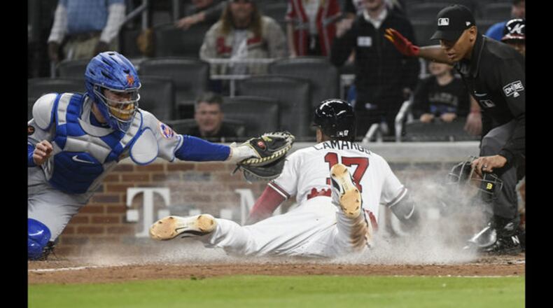 The Braves’ Johan Camargo slides across the plate with the winning run on Ender Inciarte’s walk-off bunt single in the ninth inning Saturday. (AP Photo/John Amis)