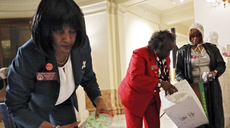 State Reps. Gloria Frazier (left), D - Hephzibah, and Sandra Scott, D - Rex, put out feminine products before the press conference. Bob Andres / bandres@ajc.com