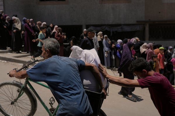 Palestinians carry bags of flour distributed by the World Food Programme (WFP) in Gaza City, northern Gaza Strip, Saturday, July 12, 2025. (AP Photo/Jehad Alshrafi)