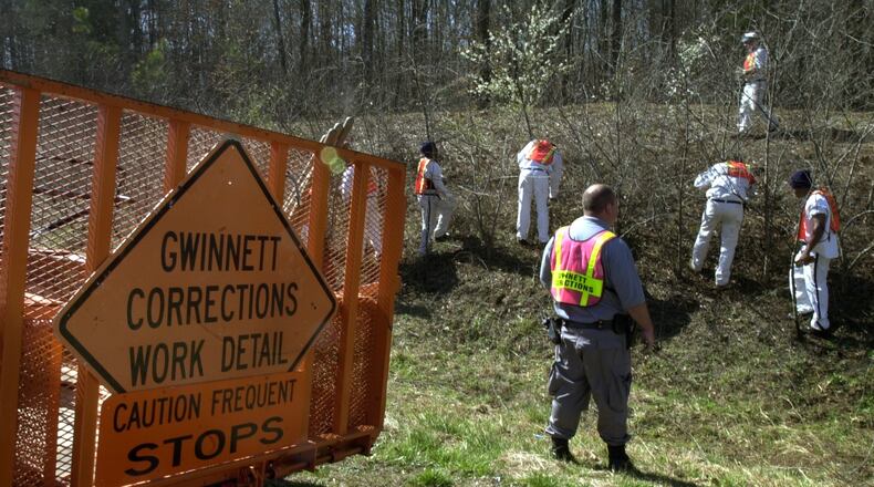 In this 2002 AJC file photo, inmates from the Gwinnett Department of Corrections work detail works alongside Ronald Reagan Parkway in Lilburn. FILE PHOTO