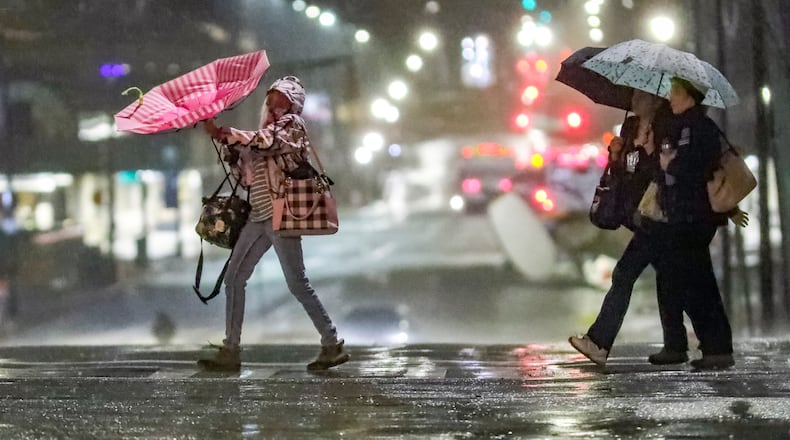 Umbrellas were hold to control for some people on Linden Avenue at West Peachtree Street in midtown Atlanta on Monday, Feb. 12, 2024. (John Spink / John.Spink@ajc.com)