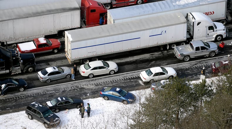 In this view looking at I-75 north at Moores Mill Rd., motorists get out of their vehicles to chat near abandoned cars along the ice-covered interstate after a winter snow storm slammed the city with over 2 inches of snow that turned highways into parking lots creating massive traffic jams lasting through Wednesday, Jan. 29, 2014, in Atlanta.