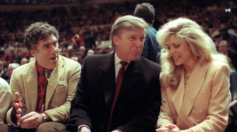FILE - Actor Elliott Gould, left, joins Donald Trump, center, and Marla Maples at courtside during an NBA basketball game between the Phoenix Suns and the New York Knicks at Madison Square Garden, in New York, March 6, 1991. (AP Photo/Steve Freeman, File)