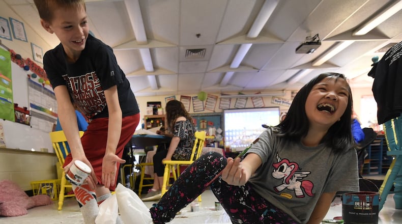 Cason Bone (left) points out the shoe slips Kiki Chen (right) and other students have to wear while painting in a preparation session for the restaurant in Marietta, Georgia, on March 22, 2017.