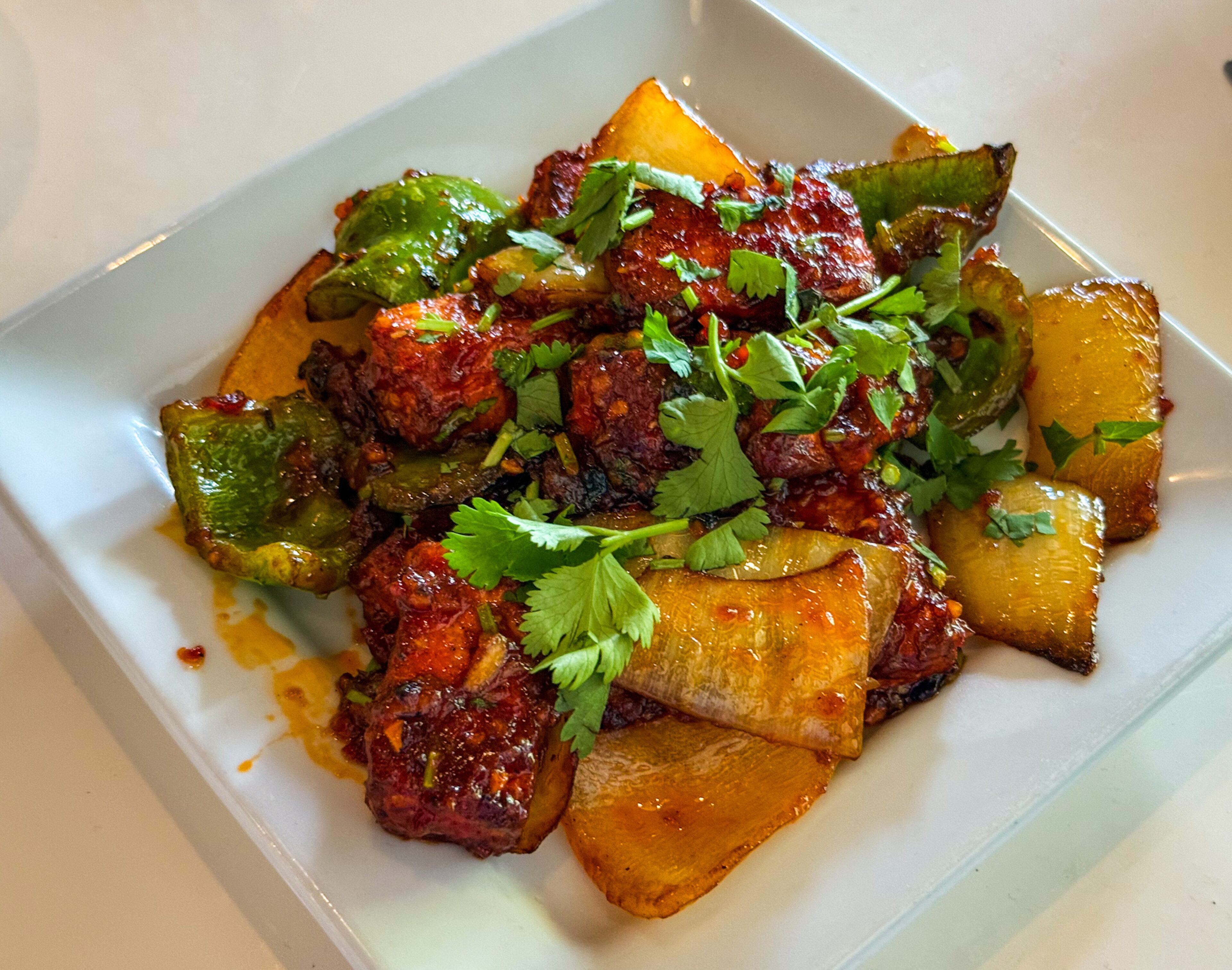 Ruchi's chili ponir appetizer includes house-made cheese (ponir) cut into pieces, fried and coated in a heavily spiced sauce. (Henri Hollis/AJC)