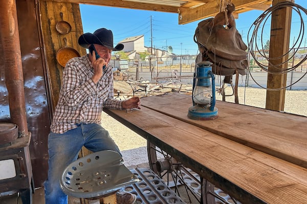 Rancher Brantley Baird takes a phone call while sitting in the shade at his pioneer museum in Joseph City, Ariz., Wednesday, April 23, 2025. (AP Photo/Susan Montoya Bryan)