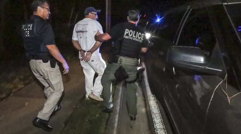 Federal immigration officers take Jose Serrano (center), a Mexican national with felony convictions, into custody in 2016 in Austell. JOHN SPINK/JSPINK@AJC.COM