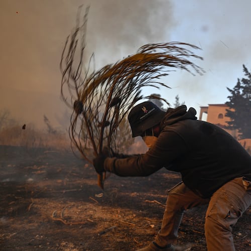 A volunteer tries to extinguish small flames during a wildfire near Porto Germeno, northwest of Athens, Greece, Sunday, Aug. 2, 2026. (AP Photo/Michael Varaklas)