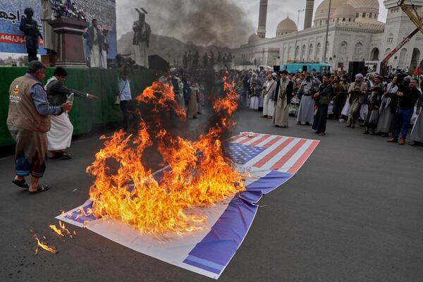 Houthi supporters burn an American and and an Israeli flags during a rally in Sanaa, Yemen, Friday, April 18, 2025. (AP Photo/Osamah Abdulrahman)