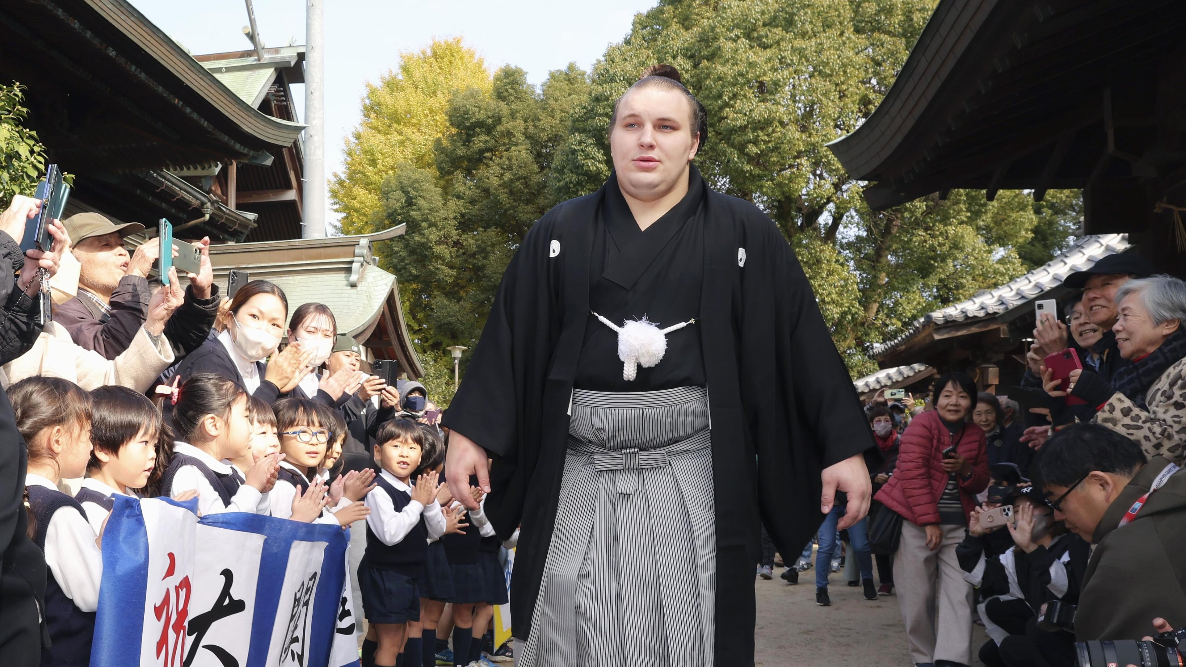 Ukrainian sumo wrestler Aonishiki, center, is celebrated by kindergarteners his promotion to the rank of ozeki in Kurume, Fukuoka prefecture, southern Japan Wednesday, Nov. 26, 2025. (Kyodo News via AP)