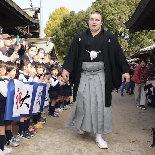 Ukrainian sumo wrestler Aonishiki, center, is celebrated by kindergarteners his promotion to the rank of ozeki in Kurume, Fukuoka prefecture, southern Japan Wednesday, Nov. 26, 2025. (Kyodo News via AP)