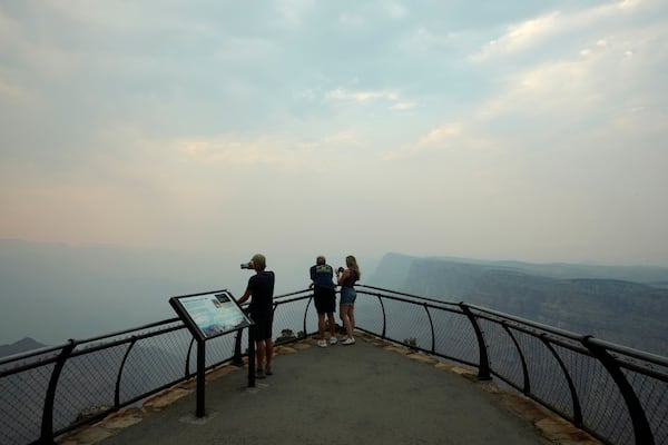 Smoke from the Dragon Bravo Fire moves over the Grand Canyon from the North Rim blocking the view for tourists at the Desert View overlook Monday, July 14, 2025, in Grand Canyon National Park, Ariz. (AP Photo/Ross D. Franklin)