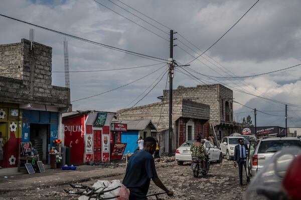 People move past an electricity pole bringing power from a Nuru solar farm in the Ndosho neighborhood of Goma, Congo, May 23, 2025. (AP Photo/Moses Sawasawa)
