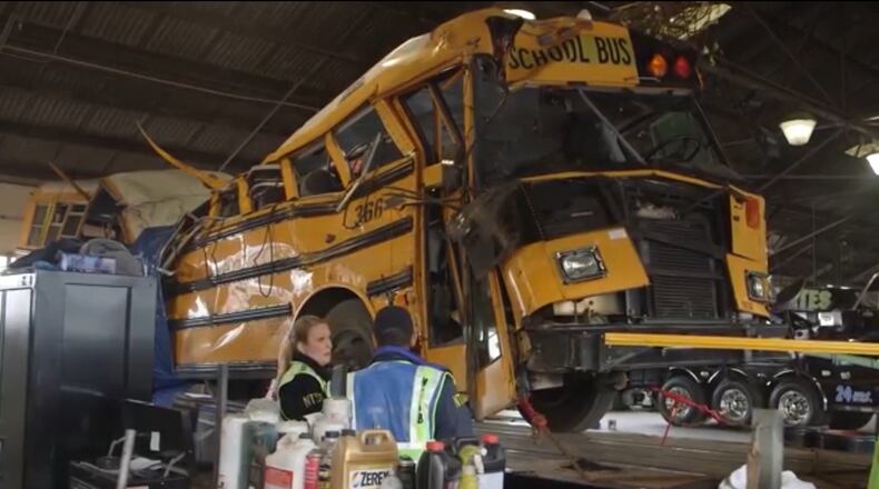 National Transportation Safety Board members with the hulk of the school bus that crashed in Chattanooga on Monday, killing at least five children. (Screen capture from NTSB video)