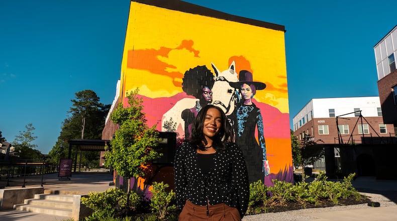 Aziza Andre' stands in front of her mural, “Renascent,” painted on the exterior of the Side Saddle Wine Saloon, on the Atlanta Beltline's Southeast trail.
