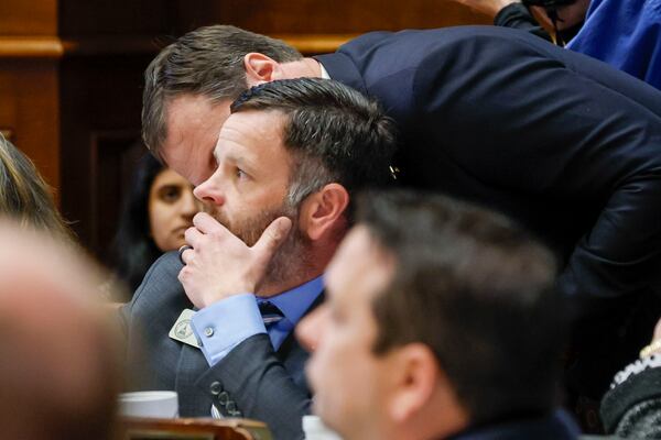 State Rep. James Burchett, R-Waycross, sponsor of Senate Bill 68, speaks to the ear of state Rep. Tim Fleming, R-Covington, while the vote is underway on Thursday, March 20, 2025. SB 68 aims to limit when people can sue businesses for some injuries and ban outside interests from funding the lawsuits. (Miguel Martinez/AJC)