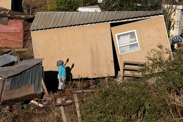 A woman takes a photograph of her damaged house, after floods swept through the area in Mthatha, South Africa, Thursday, June 12, 2025. (AP Photo/Themba Hadebe)