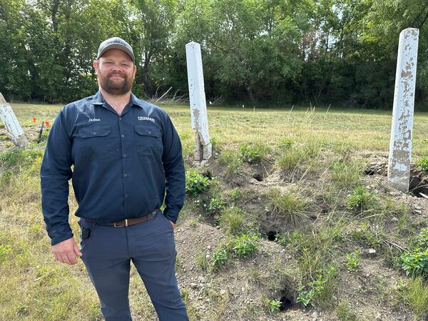 Joshua Herman, owner/operator of Herman Pest Control Services, poses for a photo on Monday, July 14, 2025, next to holes dug by Richardson's ground squirrels in Minot, N.D. (AP Photo/Jack Dura)