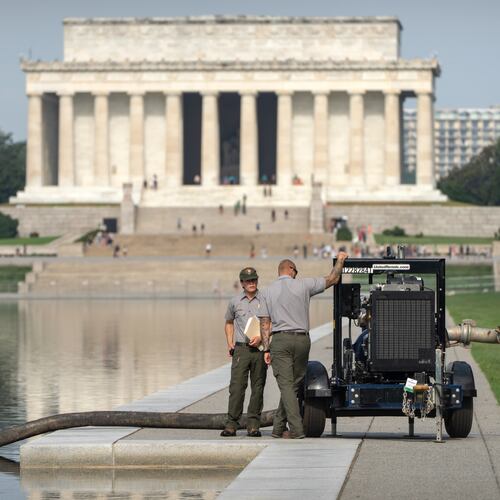 National Park Service workers stand near a pump placed next to the Lincoln Memorial Reflecting Pool, Friday, July 10, 2026, in Washington. (AP Photo/Mark Schiefelbein)