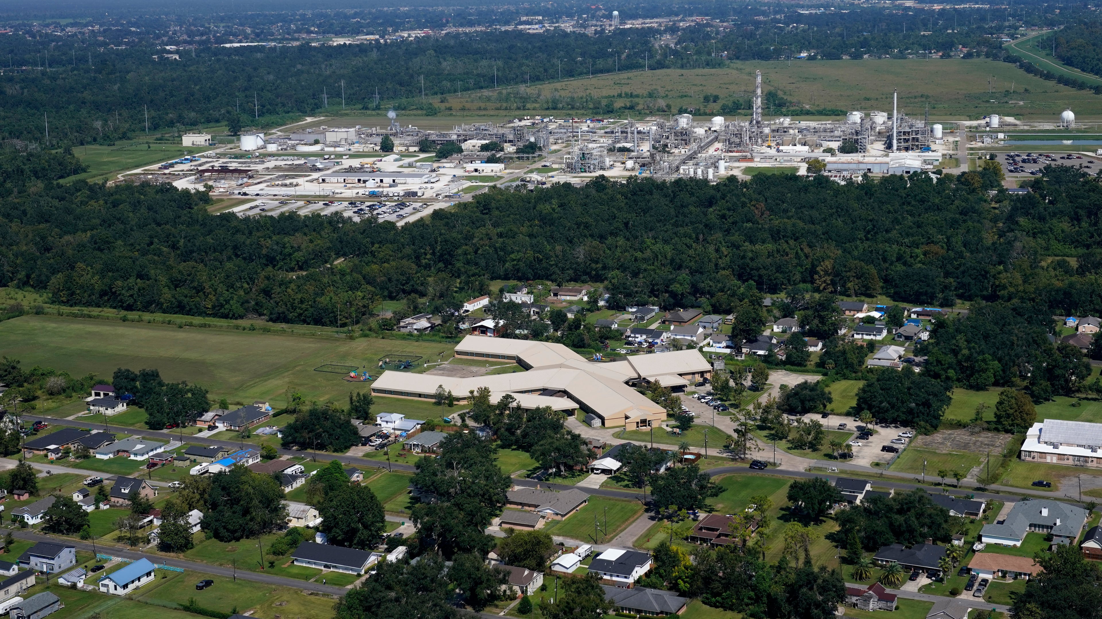 FILE - The Fifth Ward Elementary School and residential neighborhoods sit near the Denka Performance Elastomer Plant, back, in Reserve, La., Sept. 23, 2022. (AP Photo/Gerald Herbert, File)