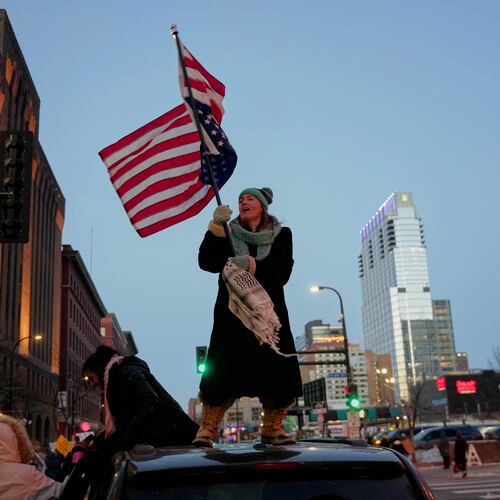 Teresa Hurst waves an upside-down American flag on top of a car during a rally against federal immigration enforcement on Friday, Jan. 23, 2026, in Minneapolis. (AP Photo/Angelina Katsanis)