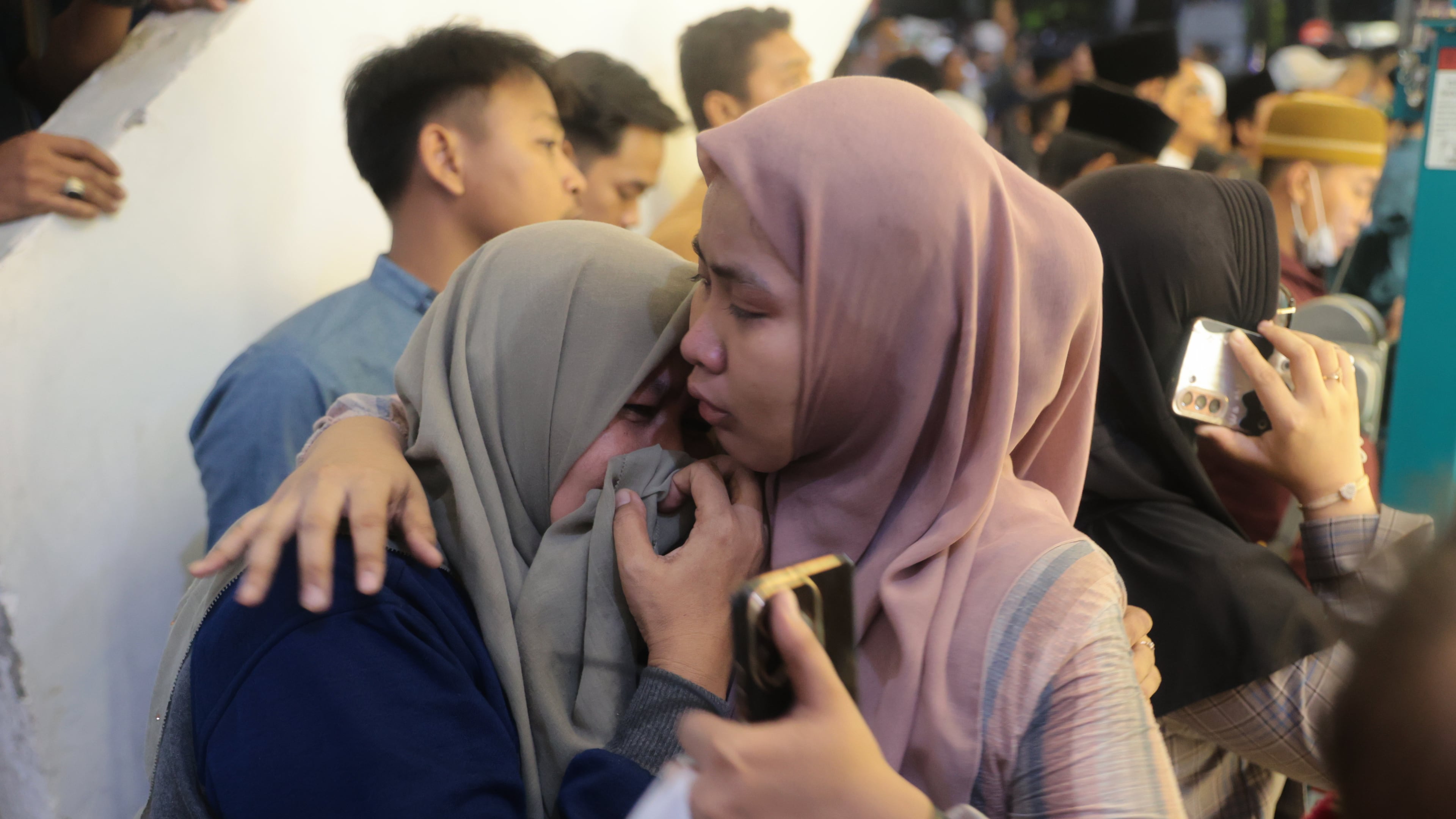 A woman is being comforted as she weeps while rescue work is underway after a building collapsed at an Islamic boarding school in Sidoarjo, East Java, Indonesia, Monday, Sept. 29, 2025. (AP Photo/Trisnadi)